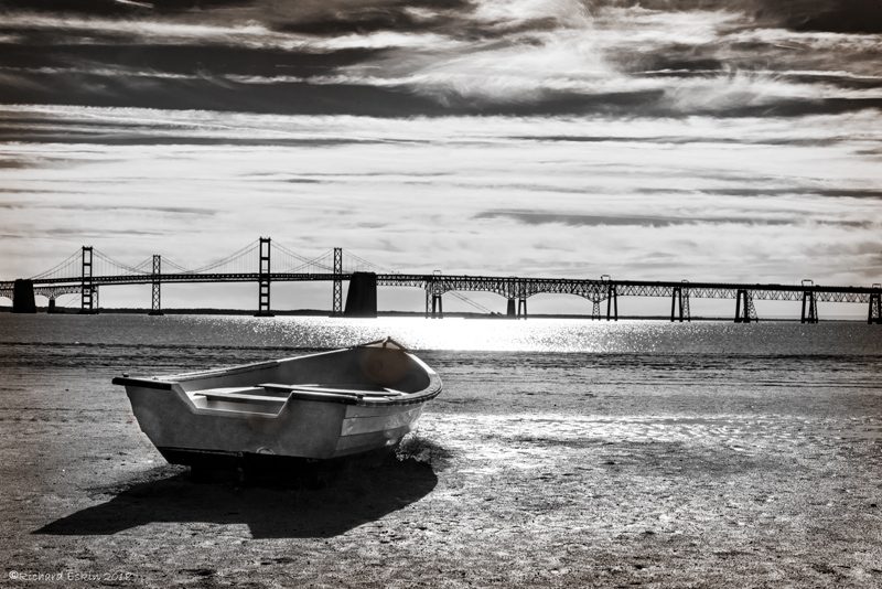 Boat on a beach with Chesapeake Bay Bridge in the background.